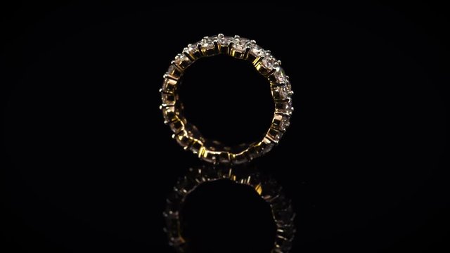 Luxury golden ring full of diamonds. Beautiful wedding jewelry on black background
