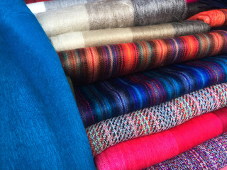 A large pile of typical colorful andean textiles found at the famous Otavalo market in Ecuador