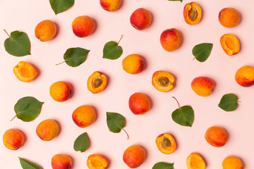 Apricots on a pink background, the flat lay image of ripe apricots and leaves	