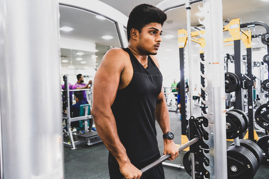 training shot of a young man in the gym, dumbbell, shrugs