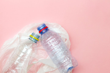 clean crumpled plastic water bottles and white plastic bag ready for recycling isolated on pink background, top view, minimal background, flat layout, waste management