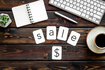Sale in shop office with word and dollar sign, keyboard, notebook on wooden background top view