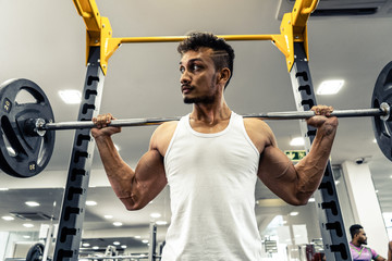 Man at the gym. Execute exercise squatting with weight, in gym