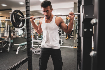 Man at the gym. Execute exercise squatting with weight, in gym