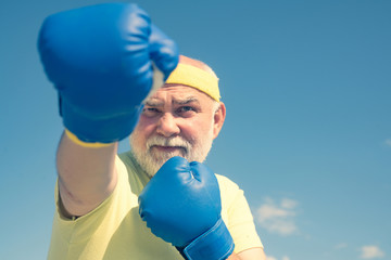 Fighter. Boxer with boxing glove. Senior man in gloves beats punching bag. Boxing. Older man...