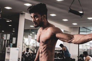 Handsome man with big muscles, posing at the camera in the gym