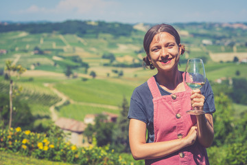 Portrait of young beautiful brunette beauty in the vineyards having a glass of white wine after harvest