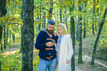 Autumn couple - Internet on a phone outdoors. Happy couple on autumn walk. Outdoor Autumn atmospheric moments and dream. Autumn couple. Sensual couple enjoying intimacy.