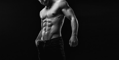 Black and white. Muscular model sports young man on dark background. Fashion portrait of strong...