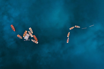 Aerial drone view of wooden boats on water surface with blue sky reflection in lake. Nature...