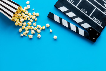 Filmmaker profession with clapperboard and popcorn on blue background top view copyspace