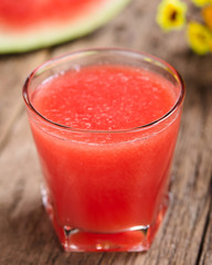 Refreshing watermelon juice on rustic wood (Selective Focus, Focus on the front of the glass rim)