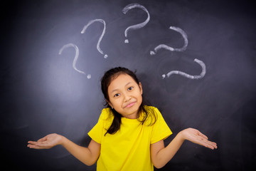 Confused little girl standing with question marks