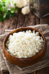 Fototapeta na wymiar Freshly grated raw cauliflower rice in wooden bowl (Selective Focus, Focus one third into the image)