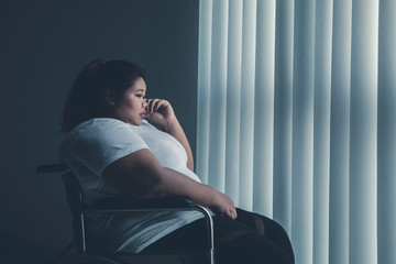 Disabled fat woman crying near the window