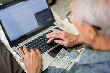 Elderly man typing on the laptop