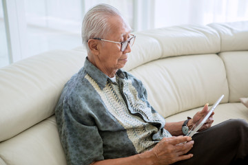 Elderly man using a digital tablet at home