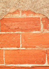 Red bricks and flaking off plaster weathered wall element / detail.