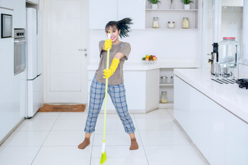 Female housekeeper dancing with a broom