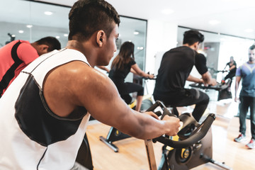 Fit people working out at spinning class in gym