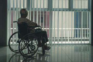 Lonely old man in the wheelchair near the window