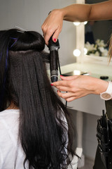 Naklejka premium Hairdresser makes hairstyle to client. Hairdressing services. Creating hairstyle. Hair styling process. Beauty service concept
