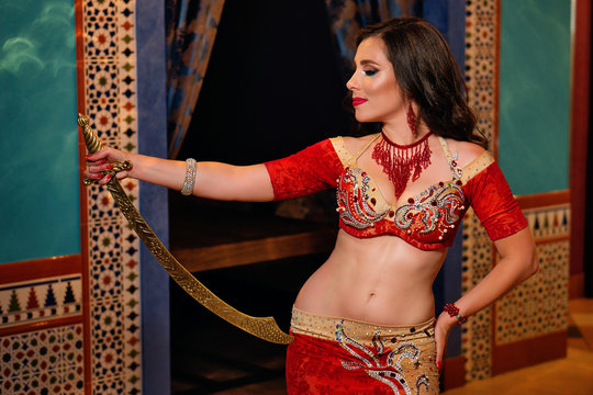 Oriental professional belly dancer in carnival shining costume with long healthy glossy hair and cane. Exotic star of bellydance. Belly Dancer During Show