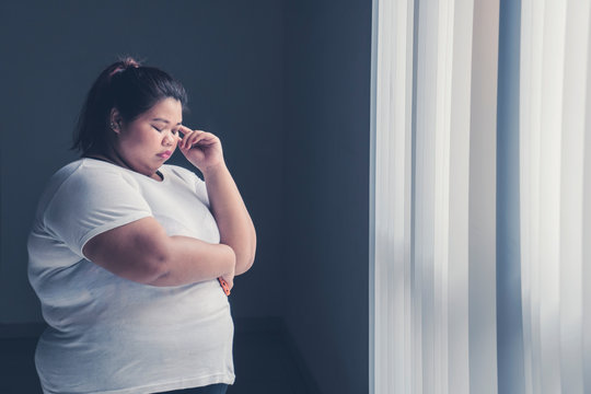 Obese woman thinking something near the window