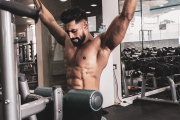 Fit man on lat pulldown machine at the health club. Work out on Pulldown Weight Machine