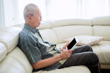 Old man using a digital tablet at home