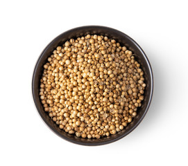Coriander seeds in black bowl isolated on white background. top view