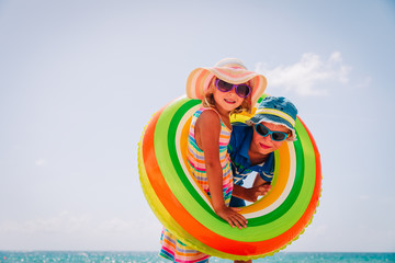 happy cute boy and girl play with floaties on beach