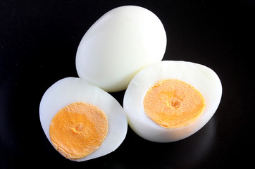 Boiled eggs and  half on a black background.