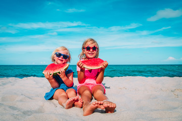 happy cute little girls eating watermelon at beach