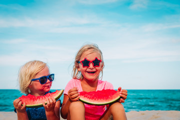 happy cute little girls eating watermelon at beach