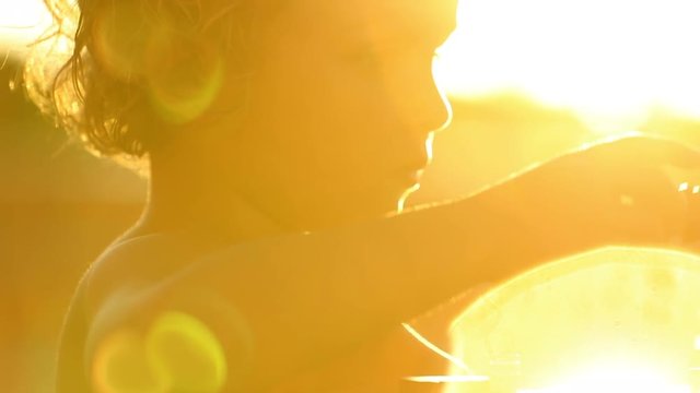 Small child playing outside in the sunlight with sunflare shining