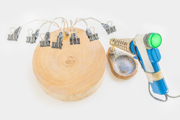 DIY multi-purpose clamps from wood cutting boards, fold back clips with an electric soldering iron and stand on the white background.