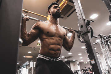 Man at the gym. Execute exercise squatting with weight, in gym