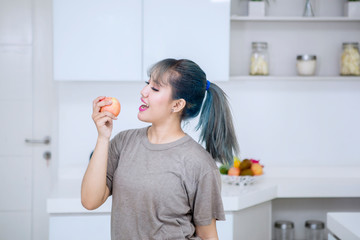 Young woman eating fresh apple in the kitchen