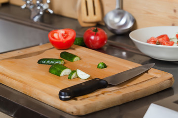 Composition with vegetables, cucumbers, tomatoes, knife closeup in the kitchen