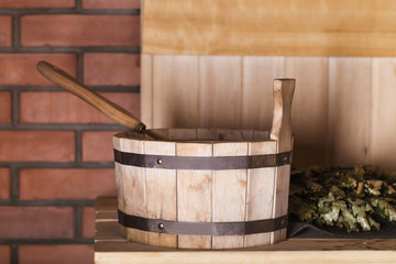 Wooden bucket with a ladle and a broom in the sauna
