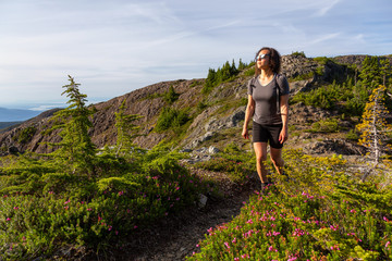 Naklejka premium Adventurous girl hiking the beautiful trail in the Canadian Mountain Landscape during a vibrant summer evening. Taken at Mt Arrowsmith, near Nanaimo, Vancouver Island, BC, Canada.