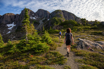 Fototapeta premium Adventurous girl hiking the beautiful trail in the Canadian Mountain Landscape during a vibrant summer evening. Taken at Mt Arrowsmith, near Nanaimo, Vancouver Island, BC, Canada.