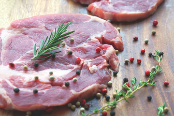 Close up of uncooked raw meat with rosemary and pepper on wooden background