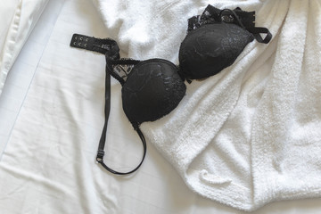 Top view of black sexy bra with hotel bath rope on the hotel bed - obrazy, fototapety, plakaty