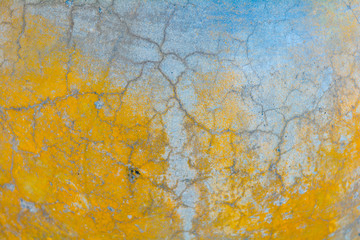 Yellow and gray cracked concrete texture. Rough surface, yellow painted spots