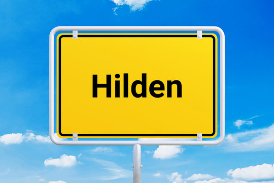 Stadt Hilden. Gelbes Schild, Ortsschild, Ortseingangsschild. Himmel mit Wolken.