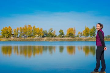 Beautiful young woman enjoying autumn by the side of a wild lake