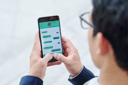 Smartphone of businessman using messenger application on his smartphone for communication with coworkers