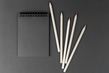 black notebook and white pencils on black background. Mock Up Notepad of black paper and white pencils are on paper background. Copy space.